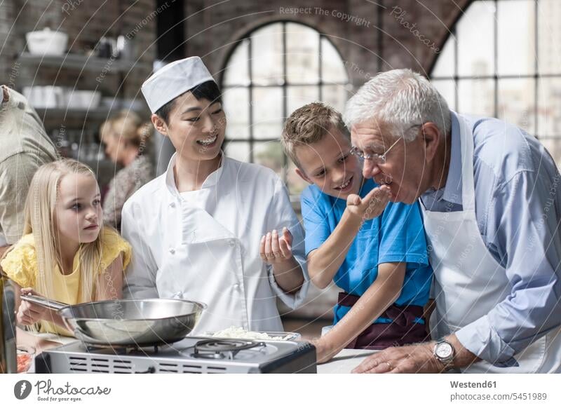 Participants and female chef cooking in cooking class kitchen group of people Group groups of people female cook persons human being humans human beings cooks