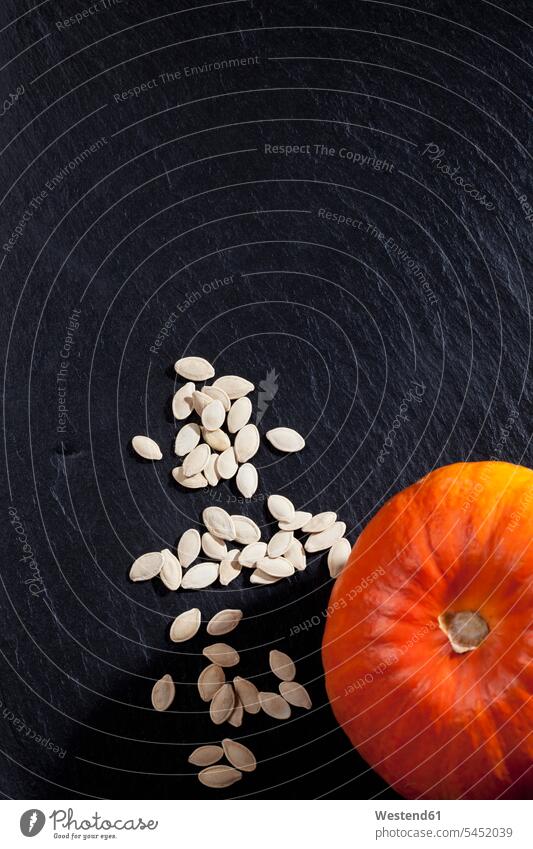 Hokkaido pumpkin and pumpkin seeds on slate black background black backgrounds Hokkaido pumpkins Red kuri squash orange overhead view from above top view