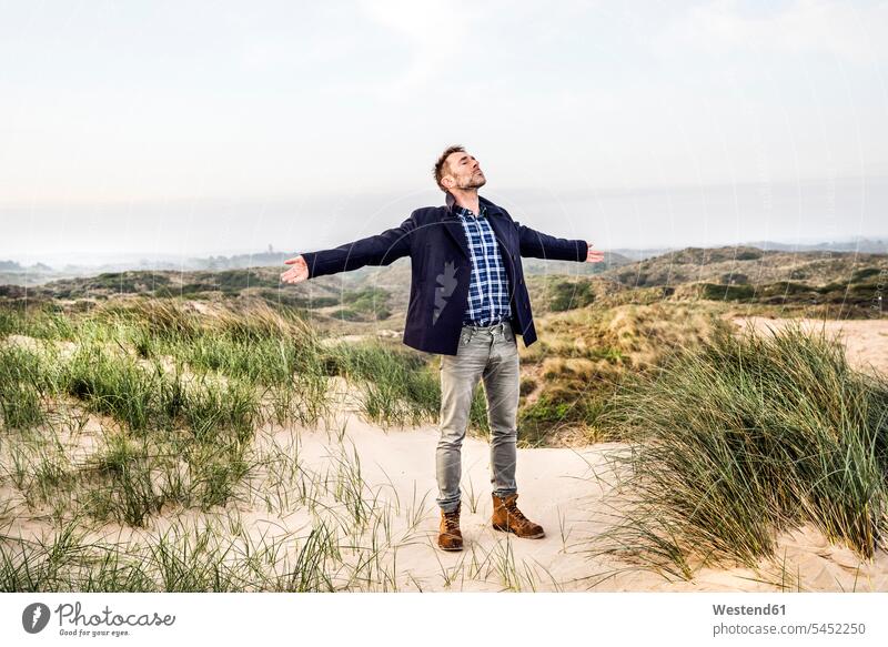 Man standing in dunes with outstretched arms beach beaches man men males sand dune sand dunes Adults grown-ups grownups adult people persons human being humans