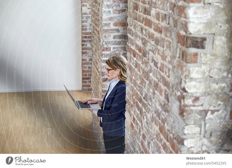 Businesswoman on modern office floor using laptop businesswoman businesswomen business woman business women Laptop Computers laptops notebook business people