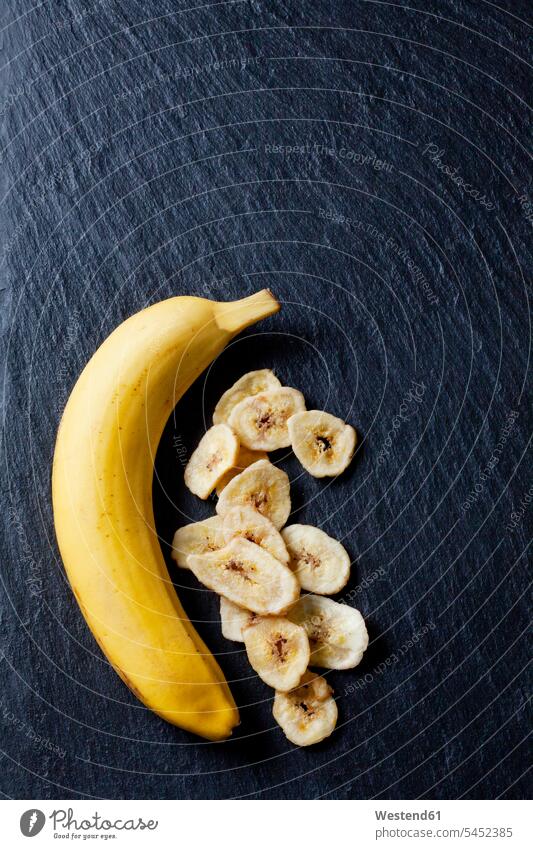 Banana and banana chips on slate black background black backgrounds dried Bananas Freshness fresh healthy eating nutrition overhead view from above top view