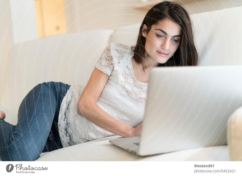 Portrait of woman on couch using laptop Laptop Computers laptops notebook settee sofa sofas couches settees females women computer computers Adults grown-ups