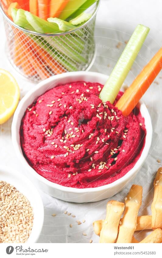 Bowl of beetroot hummus, sesame, carrot and celery crudites and breadsticks healthy eating nutrition prepared ready to eat ready-to-eat chickpeas cream paper