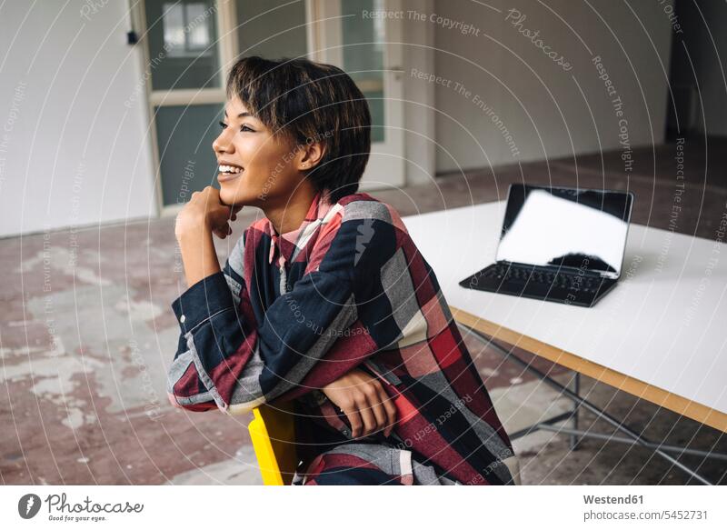 Smiling woman sitting on chair with laptop on table businesswoman businesswomen business woman business women smiling smile Laptop Computers laptops notebook