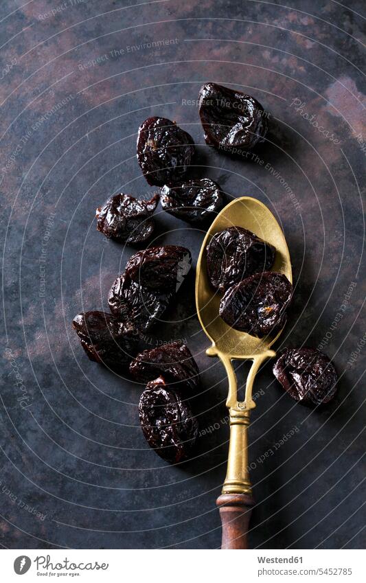 Prunes on a vintage brass spoon spoons old-fashioned brass spoons dried fruit Dried Fruits plum plums studio shot studio shots studio photograph