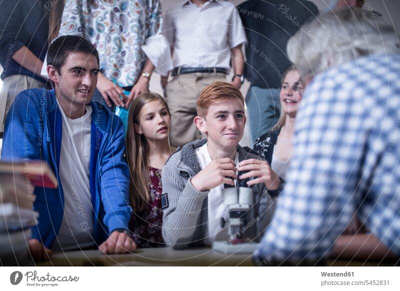 Teacher and students in science class with microscope school schools learning pupils teacher instructor teachers education pedagogue pedagogues smiling smile