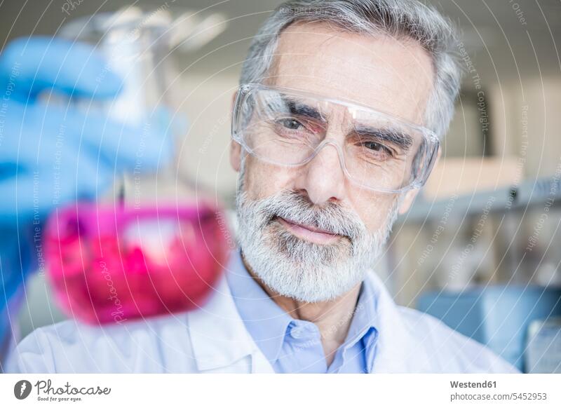 Scientist in lab holding beaker with liquid liquids laboratory Glass Beaker laboratory beaker beakers scientist science sciences scientific sample swatch