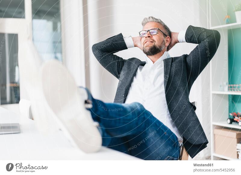 Businessman sitting in office with feet on desk Office Offices Business man Businessmen Business men business people businesspeople business world business life