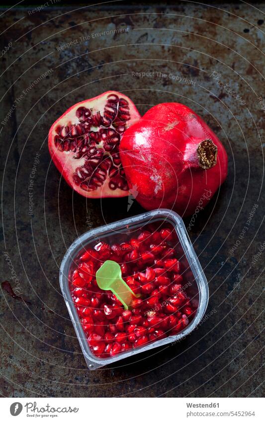 Pomegranate seed and plastic spoon in plastic box and two halves of pomegranate food and drink Nutrition Alimentation Food and Drinks Pomegranates
