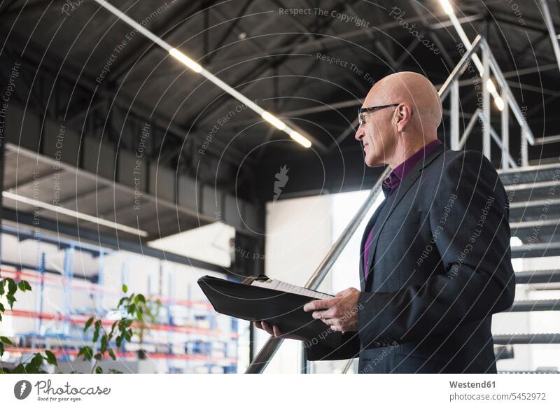 Businessman with documents on factory shop floor folder file folders portfolio portfolios files factories males Adults grown-ups grownups adult people persons