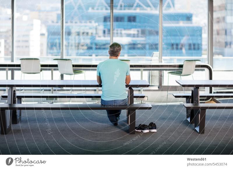 Man working in modern office, sitting on bench, rear view Seated Businessman Business man Businessmen Business men shoe shoes benches back view