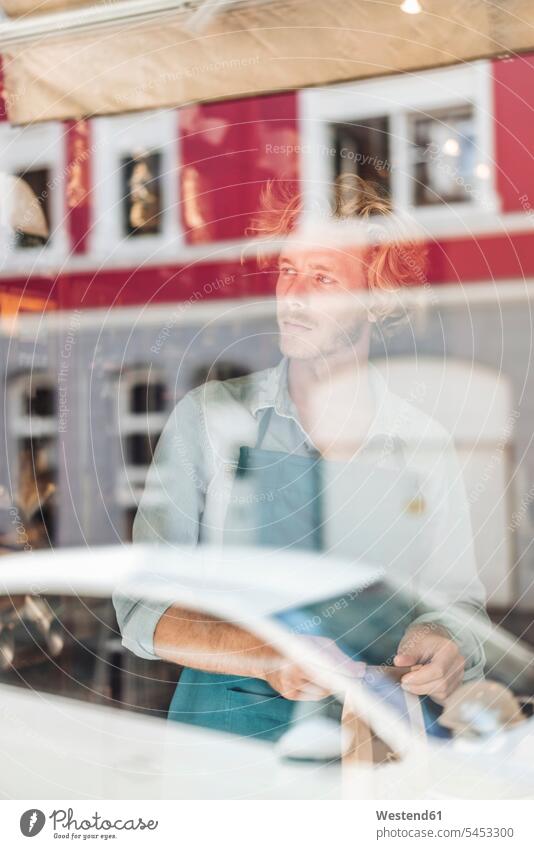 Coffee roaster in his shop behind windowpane thinking packing portrait portraits man men males window glass window glasses windowpanes Window Pane retail trade