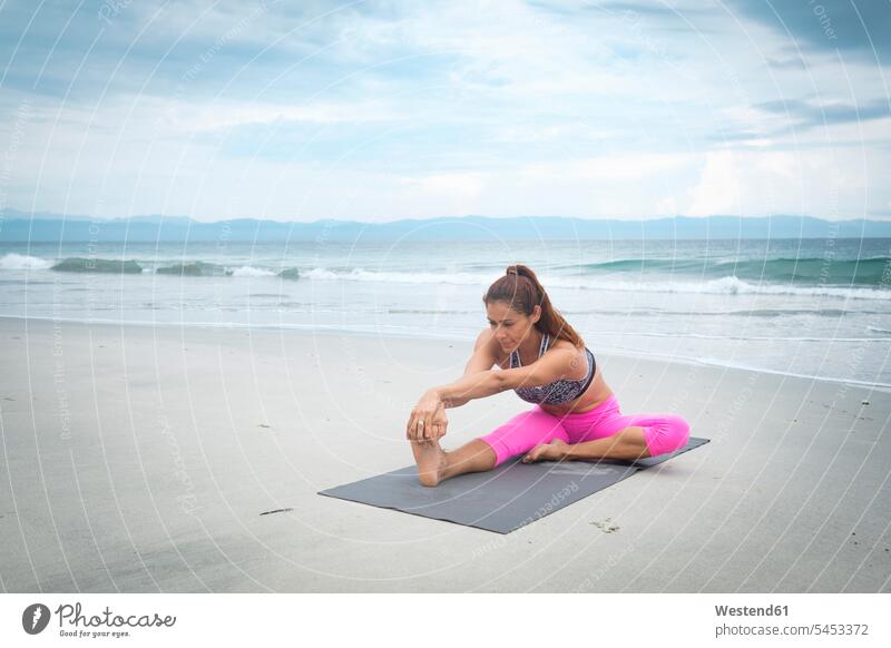 Fitness Yoga Woman Stretching On Sand. Fit Female Athlete Doing