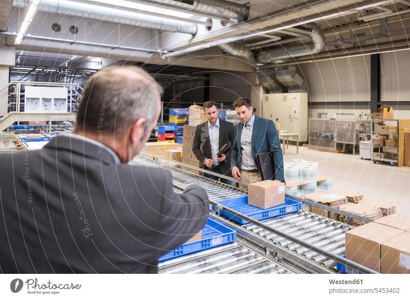 Three businessmen at conveyor belt in factory colleagues storehouse storage warehouse man males talking speaking working At Work Businessman Business man