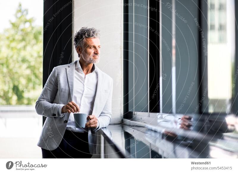 Smiling mature businessman with coffee mug looking out of window view seeing viewing smiling smile Coffee windows Businessman Business man Businessmen