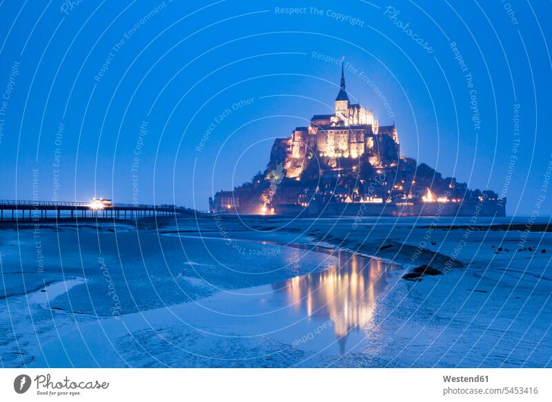 France, view to lighted Mont Saint-Michel at low tide and blue hour horizon copy space horizons Benedictine monastery island islands UNESCO World Heritage Site