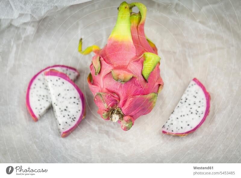 Whole dragon fruit and slices on white paper vitamines Hylocereus Megalanthus exotic Exoticism exotical outlandish healthy eating nutrition Fruit Fruits