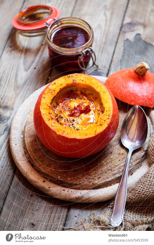 Creamed vegan pumpkin soup with chili in hollowed Hokkaido pumpkin on wooden board seasoned flavored spiced flavoured Creamed Pumpkin Soup Cream of Pumpkin Soup