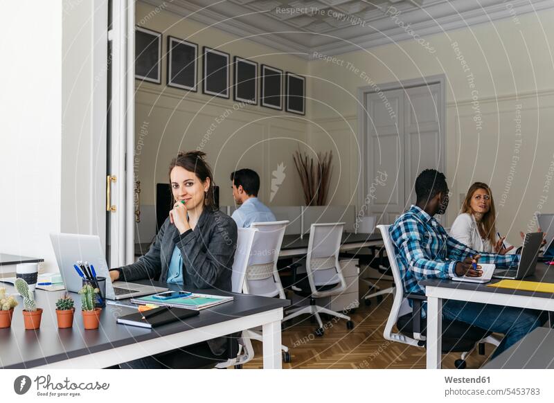 Young businesswoman using laptop, colleagues working in background team businesswomen business woman business women sitting Seated business people