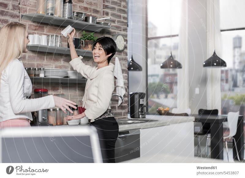 Two female friends in modern kitchen with city view smiling smile home at home mate friendship lifestyle life styles well-dressed dressed up brick wall