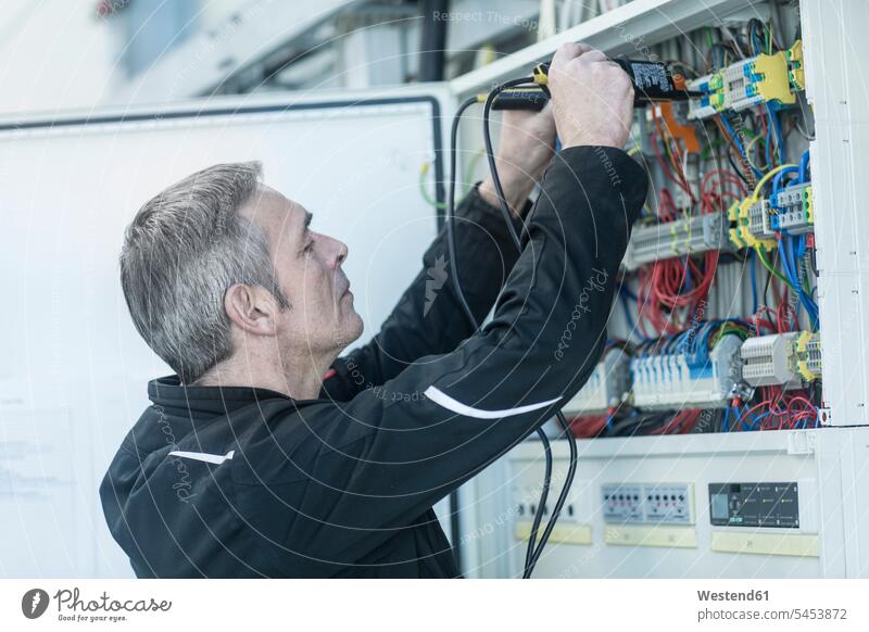 Technician working on switchboard man men males technician technicians At Work Adults grown-ups grownups adult people persons human being humans human beings