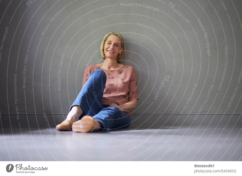 Portait of smiling mature woman at home sitting on the floor females women smile Seated floors portrait portraits Adults grown-ups grownups adult people persons