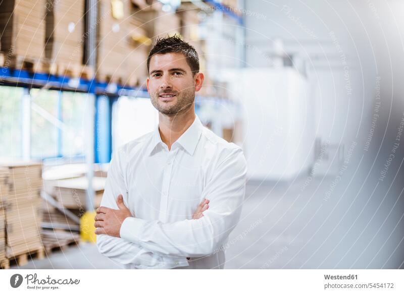 Businessman standing in warehouse, portrait storehouse storage employee clerk employees clerks factory working At Work confidence confident smiling smile