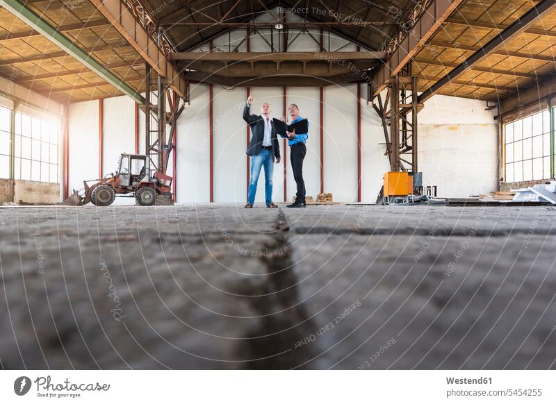 Two colleagues wearing safety vests and hard hats examining polystyrene - a  Royalty Free Stock Photo from Photocase