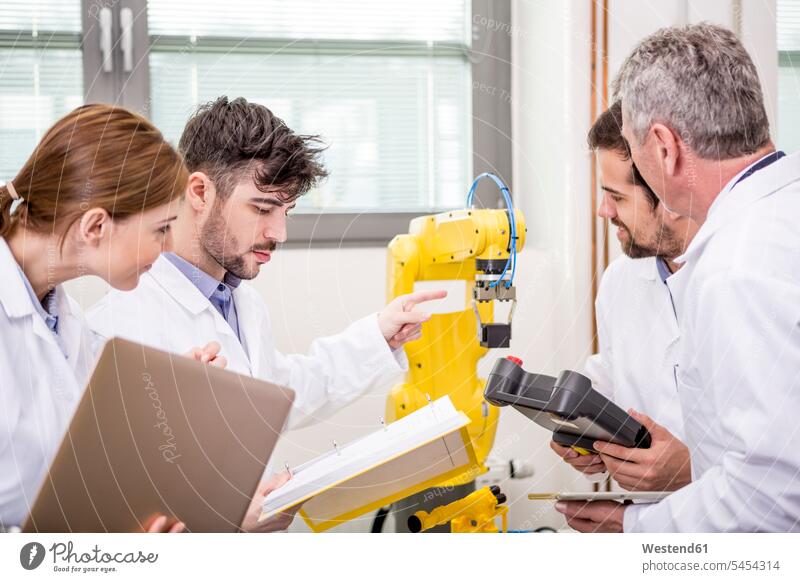 Engineers examining industrial robot engineer engineers colleagues factory factories Robot technology technologies engineering industry work meeting briefing