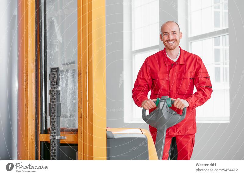 Portrait of smiling man in factory with forklift factories men males smile storehouse working At Work forklifts forklift truck forklift trucks Adults grown-ups
