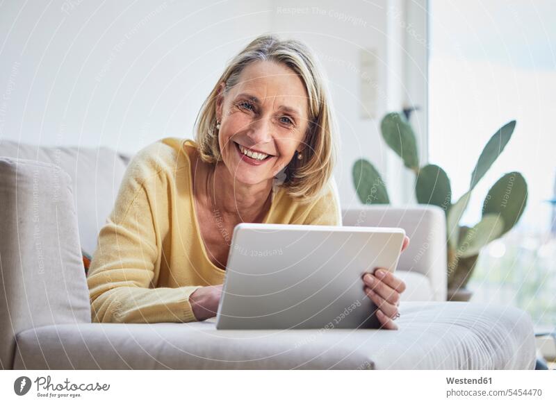 Smiling Mature Woman At Home Using Tablet On The Sofa A Royalty Free Stock Photo From Photocase