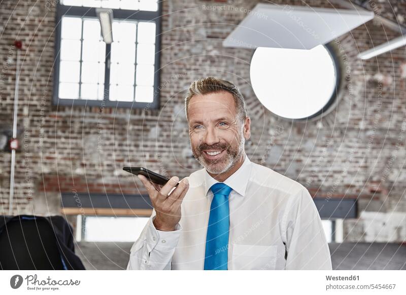 Smiling businessman using cell phone in a loft smiling smile Businessman Business man Businessmen Business men mobile phone mobiles mobile phones Cellphone