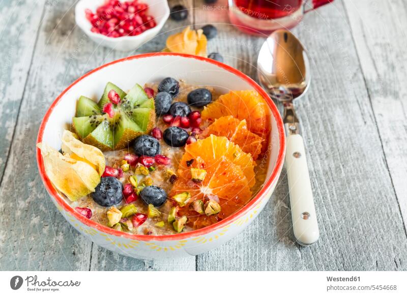 Superfood breakfast with porridge, amaranth, various fruits and pistachios Glass Drinking Glasses rich in vitamines sliced fruity Physalis Cape gooseberry