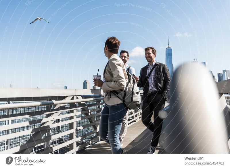 USA, colleagues walking at New Jersey waterfront smiling smile going talking speaking footbridge foot bridges water's edge waterside shore Drink beverages