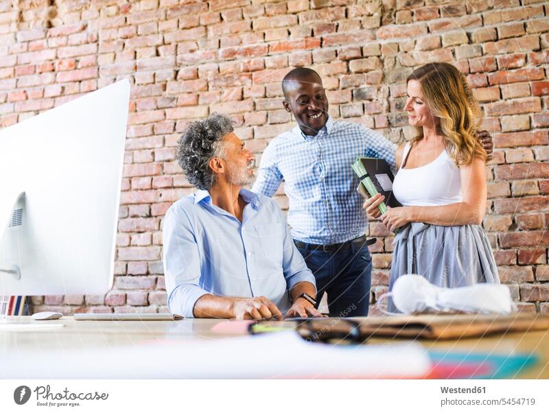 Smiling colleagues working together at desk in office At Work smiling smile desks offices office room office rooms Table Tables workplace work place