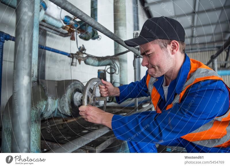 Worker turning valve in factory valves worker blue collar worker workers blue-collar worker working At Work Job Occupation man men males Adults grown-ups
