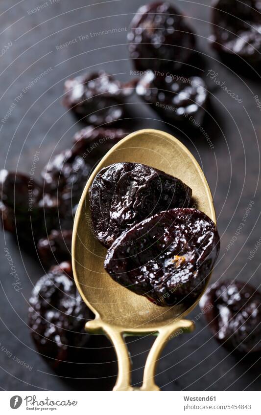 Prunes on a vintage brass spoon spoons old-fashioned brass spoons dried fruit Dried Fruits plum plums studio shot studio shots studio photograph