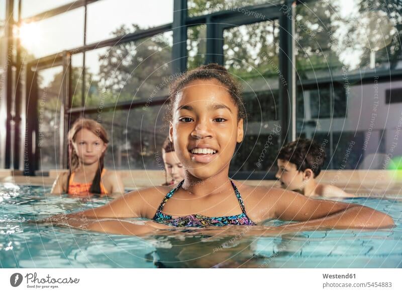 Portrait of smiling girl with friends in indoor swimming pool swimming bath females girls indoor swimming pools portrait portraits smile child children kid kids