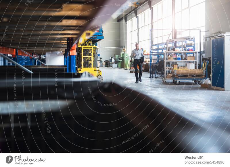 Man walking in industrial hall going man men males working At Work factory factories Adults grown-ups grownups adult people persons human being humans