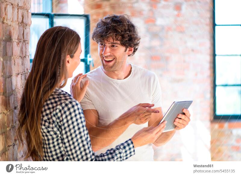 Two young entrepreneurs viewing loft for a start-up company, reading rental contract on digital tablet startup young business start up startup company startups