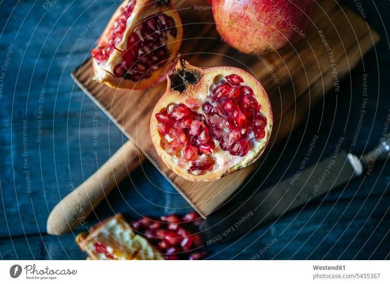 Sliced and whole pomegranate on cutting board nobody red knife knives Freshness fresh healthy eating nutrition peel peels fruit skin Fruit Fruits diagonal