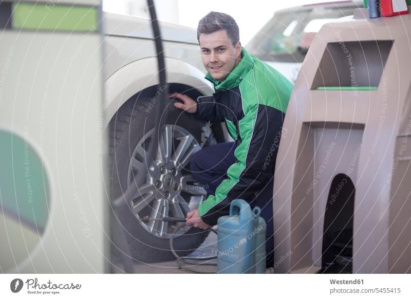 Man filling car tyres with air at fuel station petrol attendant gas station attendant automobile Auto cars motorcars Automobiles motor vehicle road vehicle