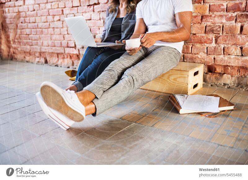 Businessman and woman sitting in a loft, using laptop, founding a start-up company Laptop Computers laptops notebook startup young business start up