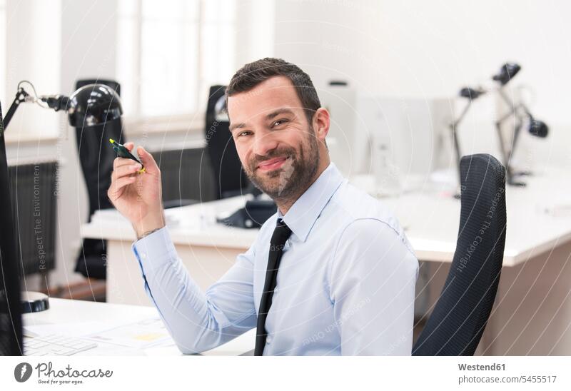 Businessman with yellow marker looking at camera working At Work smiling smile sitting Seated Business man Businessmen Business men looking to camera