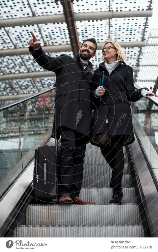 Businessman and businesswoman on escalator Business man Businessmen Business men moving staircase moving stairs Escalators businesswomen business woman