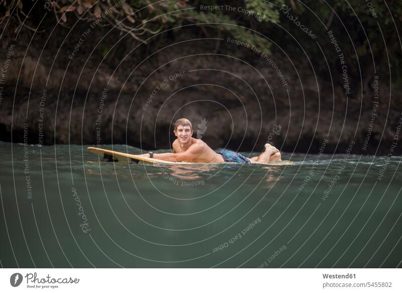 Indonesia, Java, man lying on surfboard on the sea surfing surf ride surf riding Surfboarding Sea ocean laying down lie lying down surfer surfers surfboards