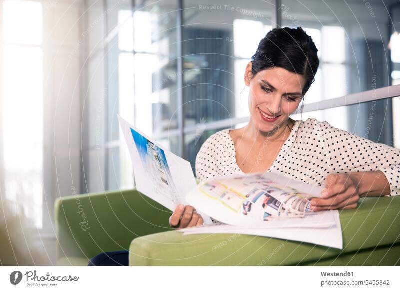 Businesswoman sitting on a couch in the office, looking at documents caucasian caucasian ethnicity caucasian appearance european Outline Planning planning