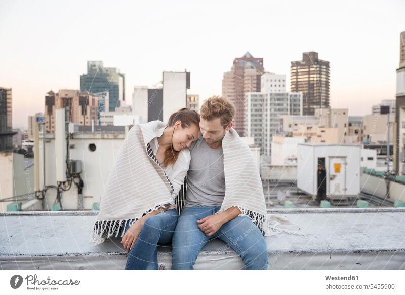 Romantic couple sitting on rooftop terrace, enjoying the view roof terrace deck happiness happy flirting Flirtation Seated parapet balustrade Falling In Love