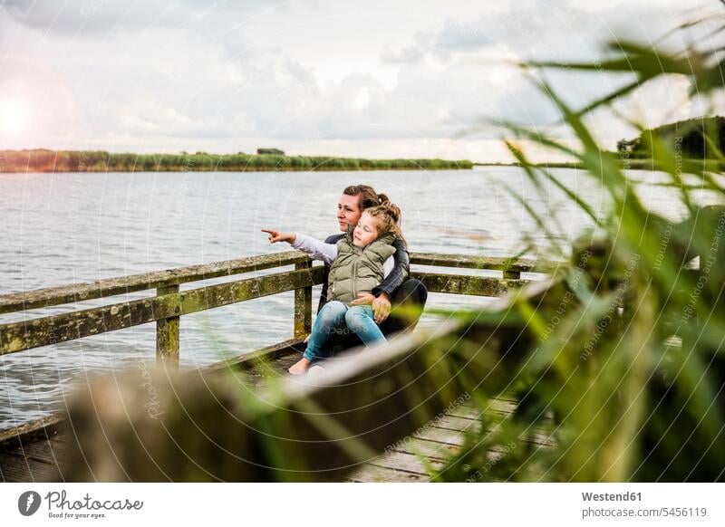 Mother and daughter on jetty at a lake jetties daughters mother mommy mothers ma mummy mama lakes girl females girls child children family families people