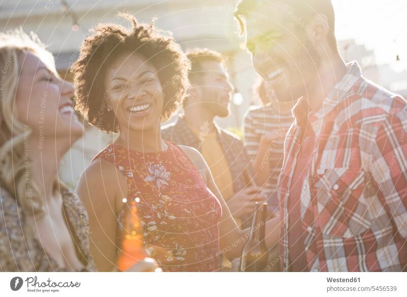 Friends having a rooftop party, chatting and drinking beer celebrating celebrate partying Party Parties roof terrace deck friends Beer Beers Ale Fun having fun